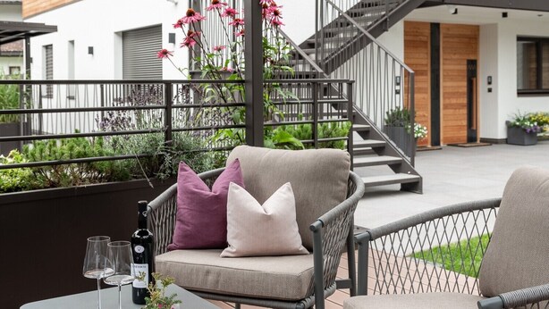 A modern outdoor seating area with a table, chairs, and a staircase leading to a wooden building. - Apartment 'Nature Berg' with Mountain View, Terrace & Wi-Fi (Luttach)