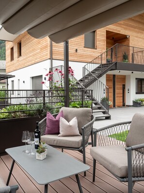 A modern outdoor seating area with a table, chairs, and a staircase leading to a wooden building. - Apartment 'Nature Berg' with Mountain View, Terrace & Wi-Fi (Luttach)