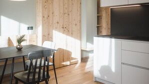A modern kitchen with wooden cabinets, a dining table with chairs, and a pendant light. - Apartment 'Nature Berg' with Mountain View, Terrace & Wi-Fi (Luttach)