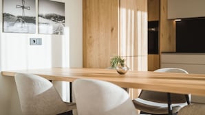 Un comedor moderno con una mesa de madera, sillas blancas y dos fotografías blanco y negro en la pared.