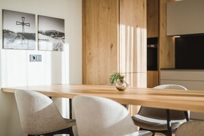 A modern dining area with a wooden table, white chairs, and two black-and-white photographs on the wall.