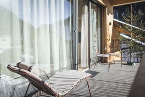 Zona d'estar exterior moderna amb una cadira relaxant i una taula petita, amb vistes a una terrassa amb barana i una vista del paisatge circumdant.