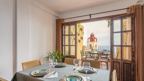 Une table à manger dressée avec des assiettes, des verres et des couverts, donnant sur un bâtiment avec un toit rouge.