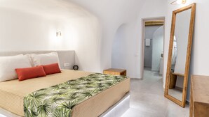 Un dormitorio moderno con una cama grande, una mesita de noche de madera, un espejo y un pasillo que conduce a un baño.