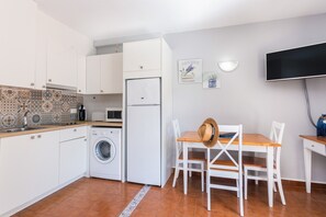 Une cuisine compacte équipée d’un lave-linge, d’un réfrigérateur, d’un four à micro-ondes et d’un coin repas avec une table et des chaises.
