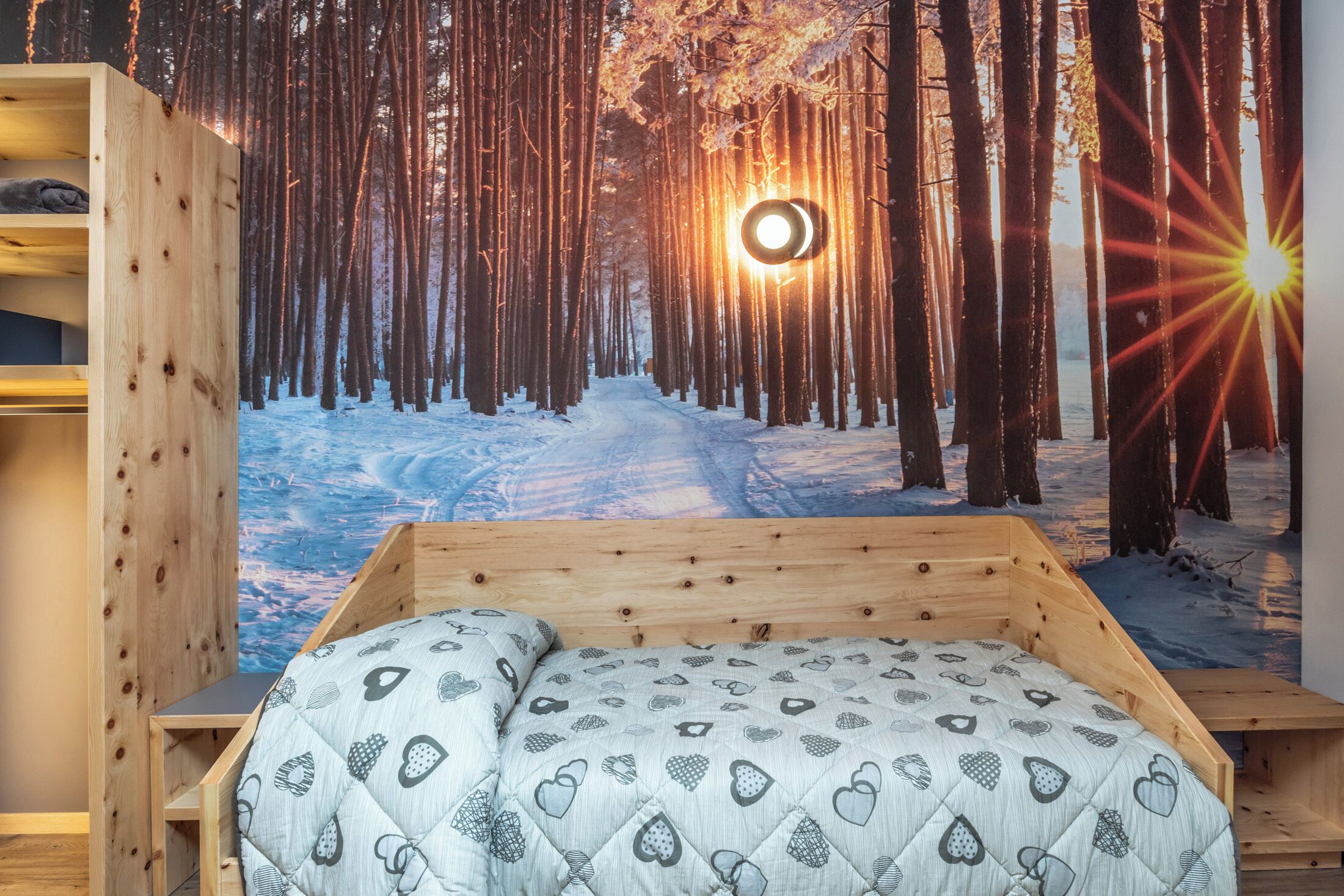 Quarto com cama, cabeceira de madeira e painel decorativo com cena de floresta.