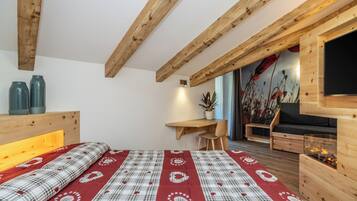 Un dormitorio con cama, vigas de madera, un escritorio, un sofá y una chimenea.