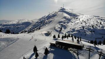 Una pista da sci innevata con una seggiovia e un edificio alla base.
