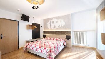 Un dormitorio moderno con cama, televisor montado, estante en la pared y radiador.