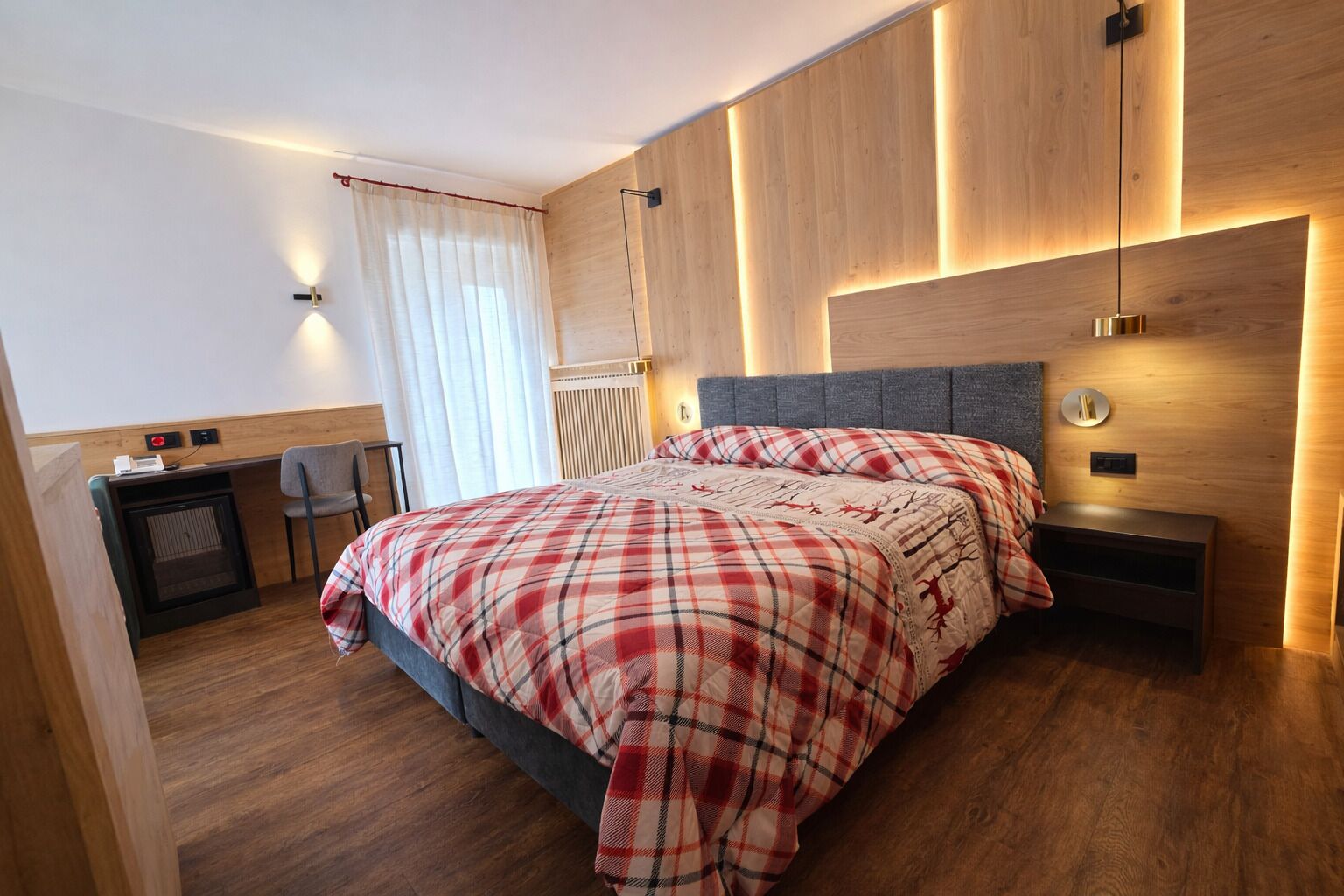 A modern bedroom with a bed, bedside tables, a desk, and a chair.