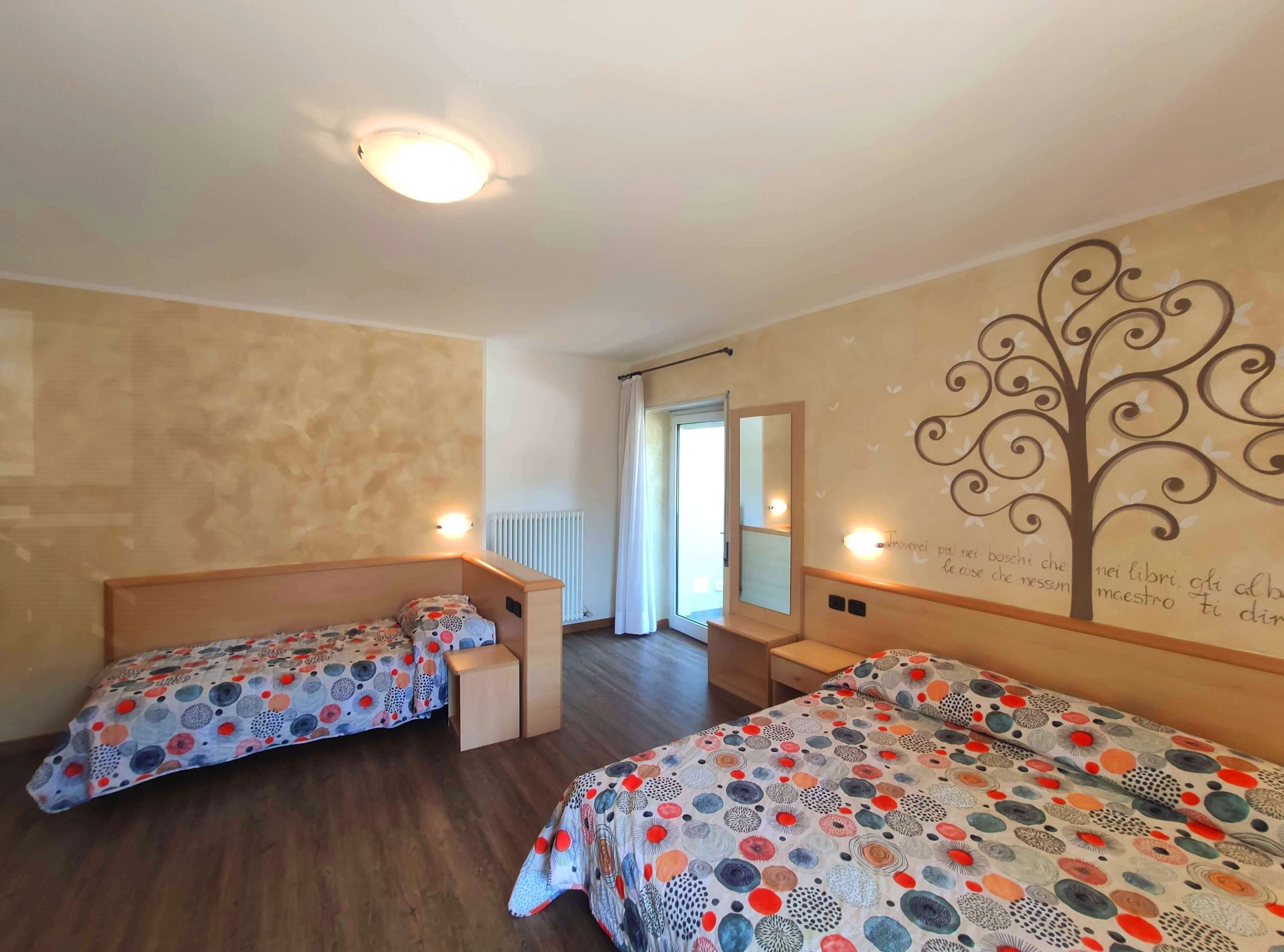 Ett hotellrum med två separata sängar, en stor spegel, en väggmålning och en taklampa.
