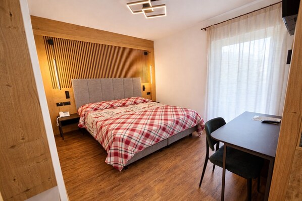 Un dormitorio con cama, mesitas de noche, escritorio y una silla.