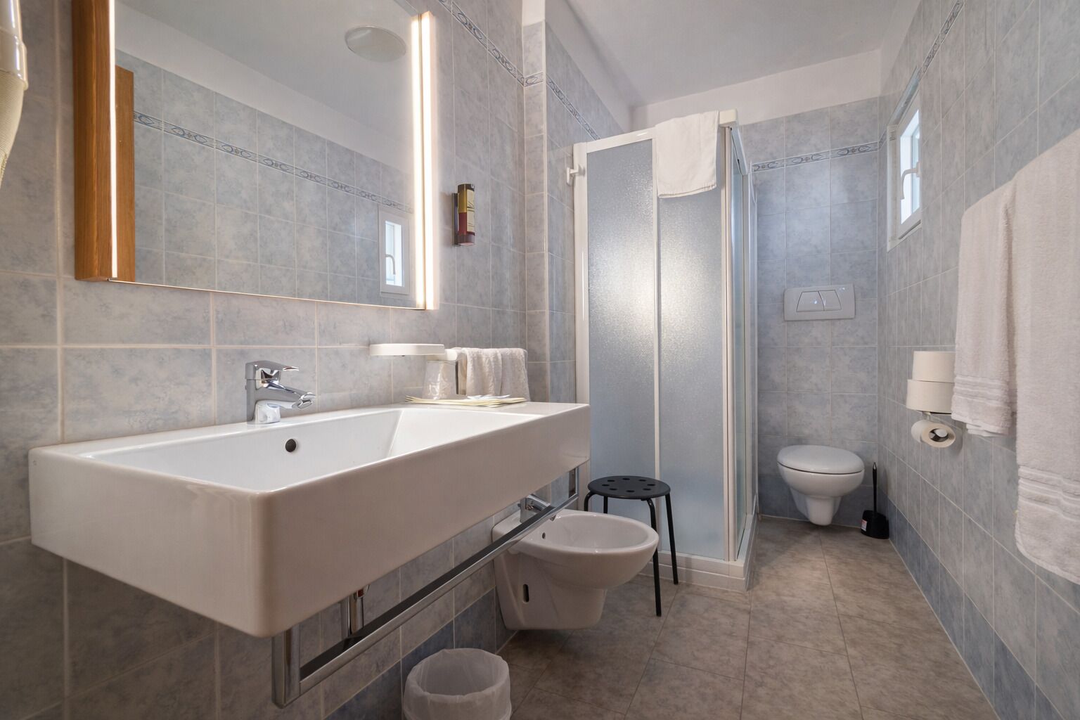 Une salle de bain moderne avec un grand lavabo, un miroir et une douche.