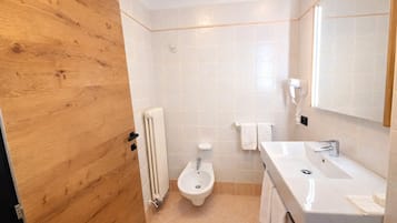 A bathroom with a wooden door, a toilet, a sink, a mirror, and a towel rack.