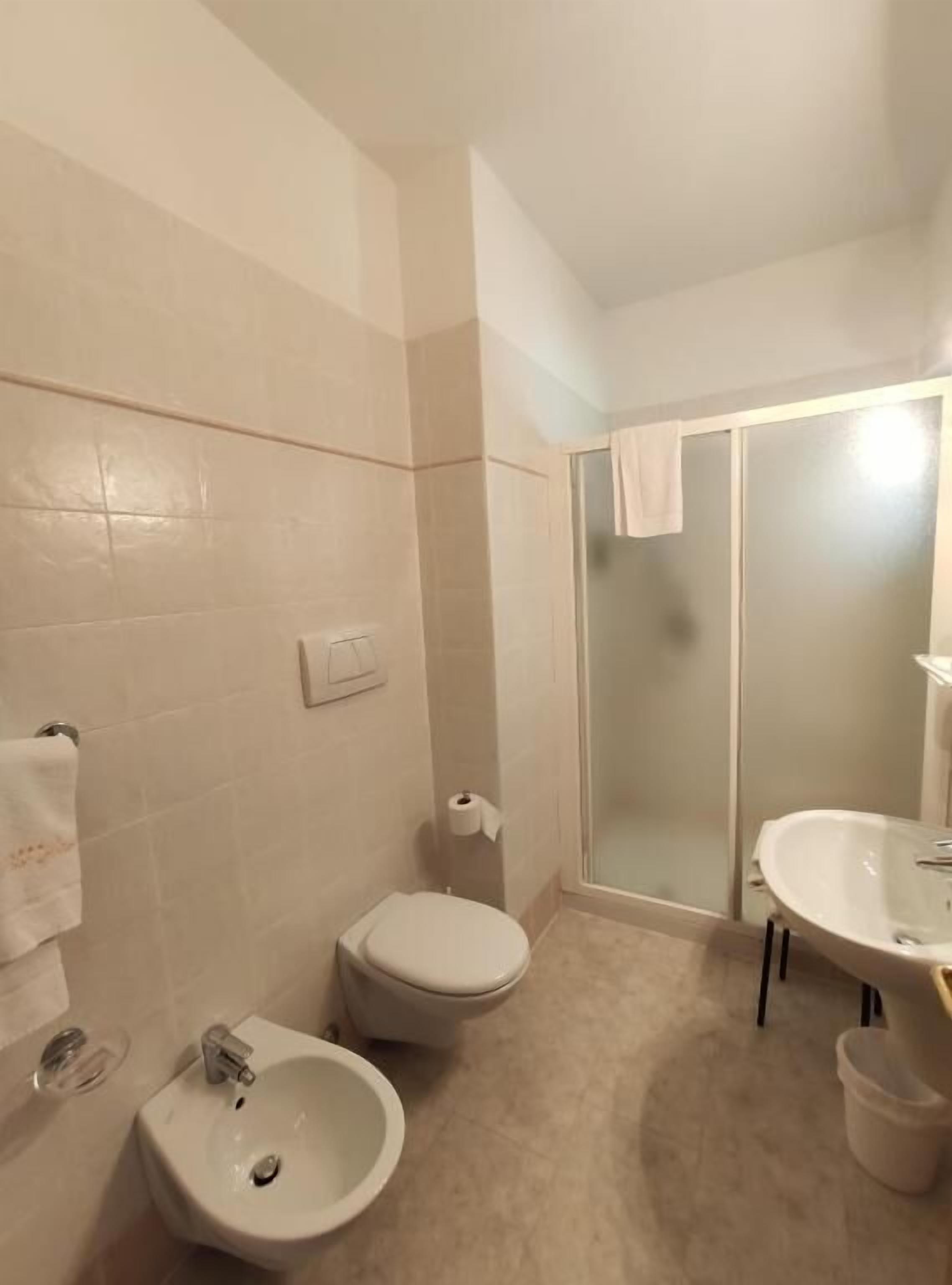 A bathroom with a toilet, sink, and shower.