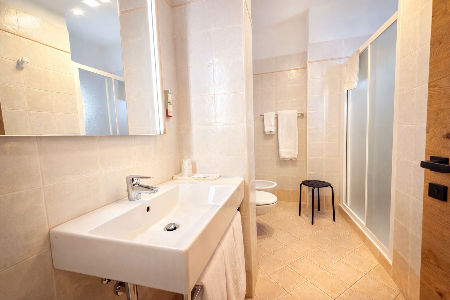 Un baño moderno con un lavamanos grande, espejo y zona de ducha.