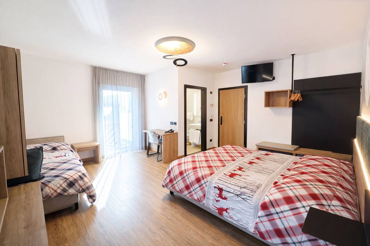 Une chambre d’hôtel avec un grand lit, un bureau, une chaise, une télévision et une armoire.