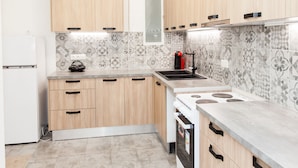 A modern kitchen with wooden cabinets, a built-in stove, and a patterned backsplash.