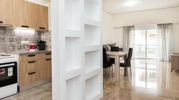 A modern kitchen with wooden cabinets, a white backsplash, and a dining area with a table and chairs.