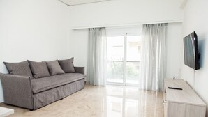 A modern living room with a grey sofa, a wooden cabinet, and a TV on the wall.