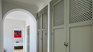 A hallway with a tiled floor, a blue chair, and a bed with a red and purple painting. - Holiday Apartment with Private Pool near the Beach with 2 Terraces and Wi-Fi (Nerja)