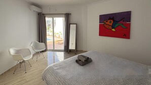 A modern hotel room with a large bed, a painting, a sliding door to a balcony, and a white chair. - Holiday Apartment with Private Pool near the Beach with 2 Terraces and Wi-Fi (Nerja)