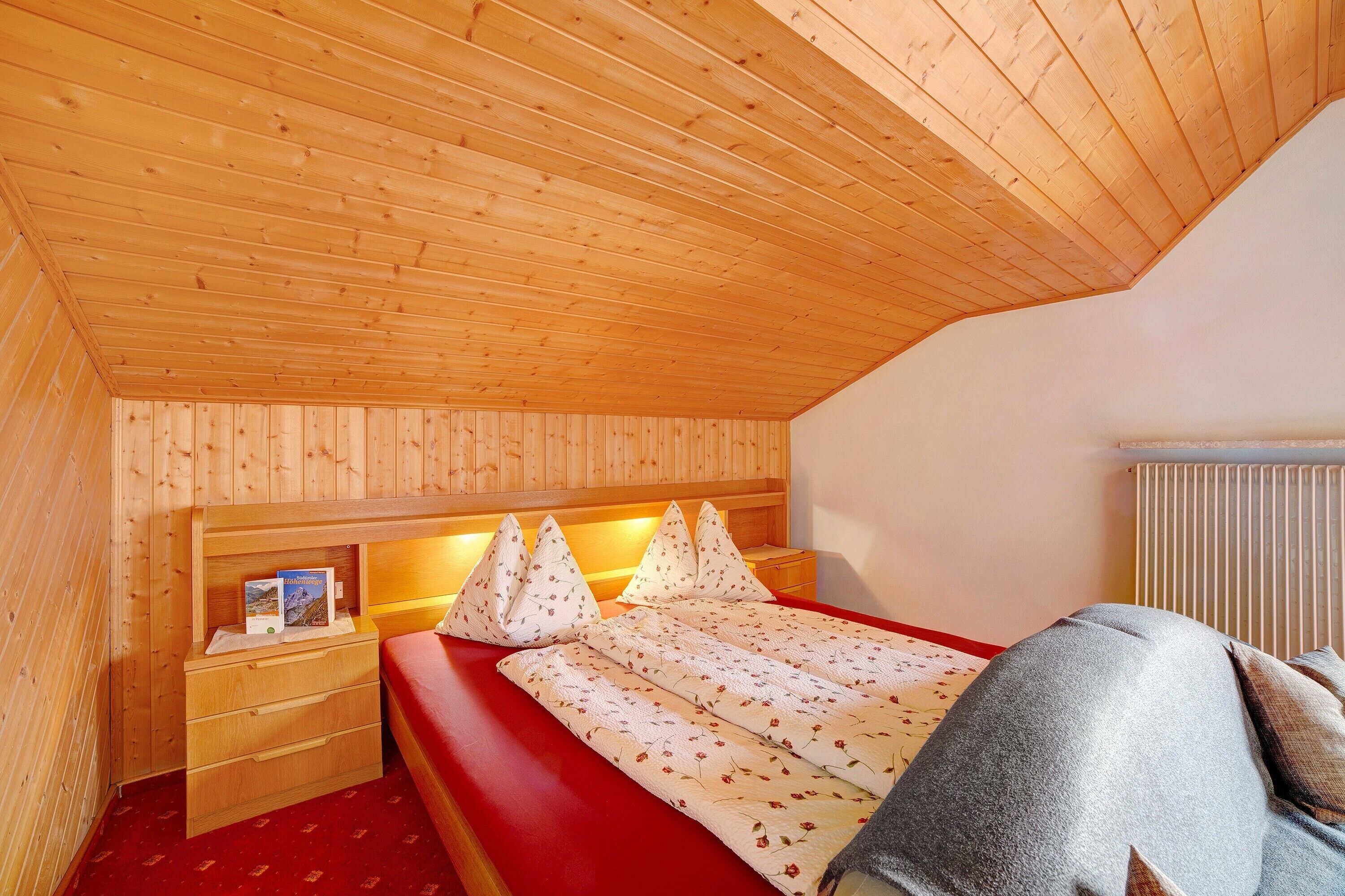 A wooden-paneled room with a bed, a nightstand, and a radiator.