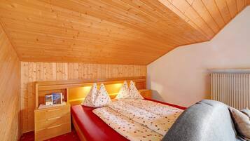 A wooden-paneled room with a bed, a nightstand, and a radiator.