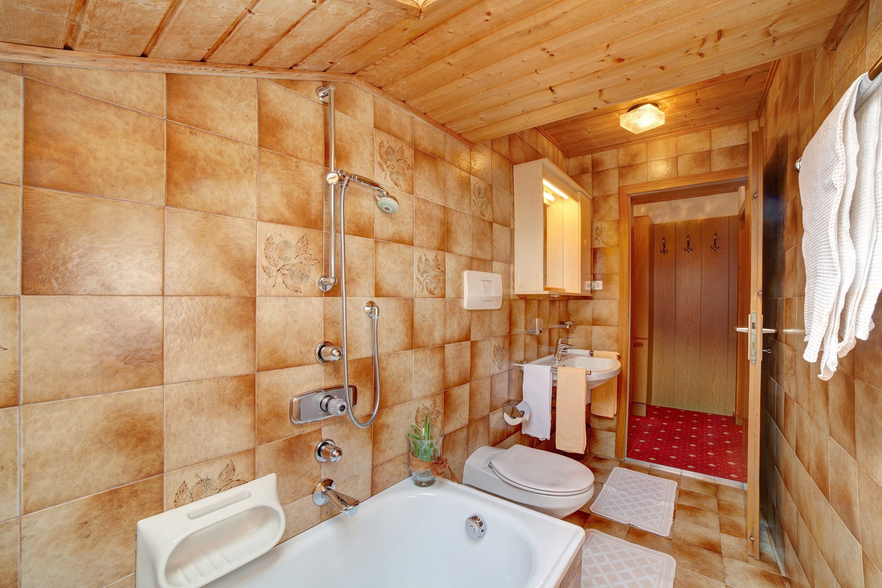 Ein Badezimmer im Holzstil mit Badewanne, Toilette und Waschbecken.
