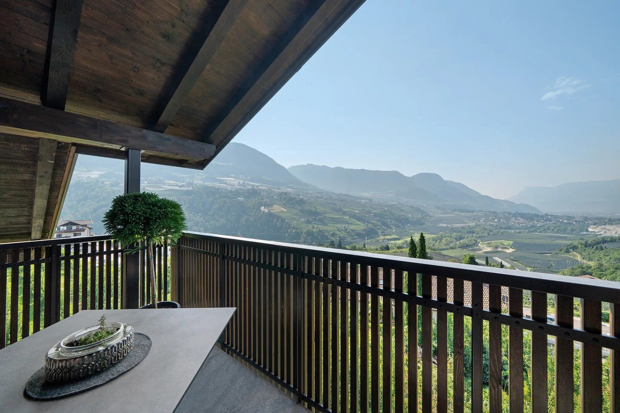 A balcony with a view of a valley and mountains.