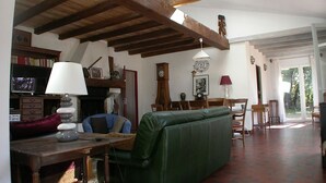 Un salon rustique avec des poutres apparentes, un canapé vert, une table en bois avec une lampe et une cheminée.