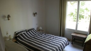 Une chambre à coucher avec un lit, des tables de chevet, une chaise et une fenêtre.