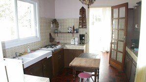 Une cuisine de taille réduite, équipée d’un évier, d’une cuisinière et d’une table en bois.