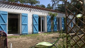 Un bâtiment avec des volets bleus, un patio et une clôture en treillis.