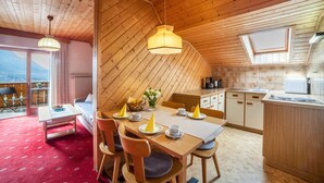 A wooden interior with a dining area, kitchen, and a balcony with a view. - Holiday Apartment 'Sankt Corbinian 4' with Mountain View, Balcony, Shared Garden & Wi-Fi (Kuens)