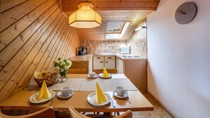 A cozy wooden cabin with a dining area, kitchen, and a clock on the wall. - Holiday Apartment 'Sankt Corbinian 4' with Mountain View, Balcony, Shared Garden & Wi-Fi (Kuens)
