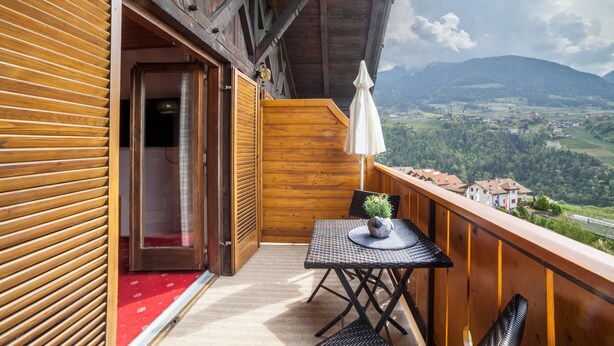 A balcony with a table, chairs, and a potted plant. - Holiday Apartment 'Sankt Corbinian 4' with Mountain View, Balcony, Shared Garden & Wi-Fi (Kuens)
