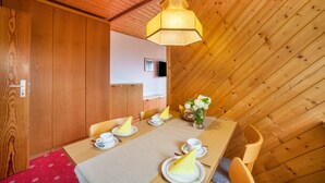 A dining area with a wooden table set for four, a hanging light fixture, and a view of a wooden ceiling. - Holiday Apartment 'Sankt Corbinian 4' with Mountain View, Balcony, Shared Garden & Wi-Fi (Kuens)