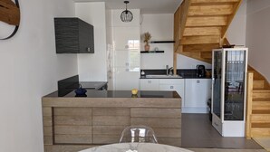 A modern kitchen with a central island, wooden accents, and a built-in refrigerator. - Central Arcachon - Bright 3* Duplex T3 with Balcony, Parking, and Modern Amenities (Arcachon)