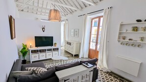Een moderne woonkamer met een bank, televisie en een eetgedeelte met een tafel en stoelen.