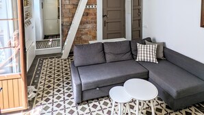 Een moderne woonkamer met een grijze hoekbank, een vloer met patroon en een loft-plafond.
