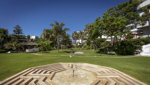 A landscaped garden with a central fountain, surrounded by a well-maintained lawn and various trees.