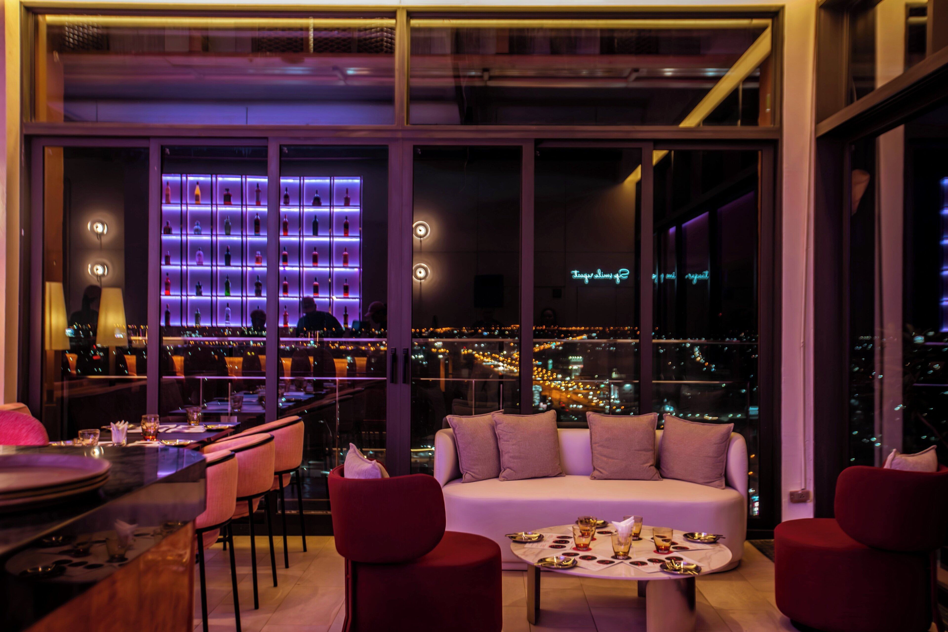A modern interior with a seating area, a bar, and a city view.