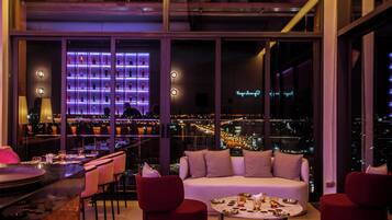 A modern interior with a seating area, a bar, and a city view.