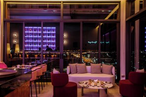 Un interior moderno con una zona de estar, un bar y vistas a la ciudad.