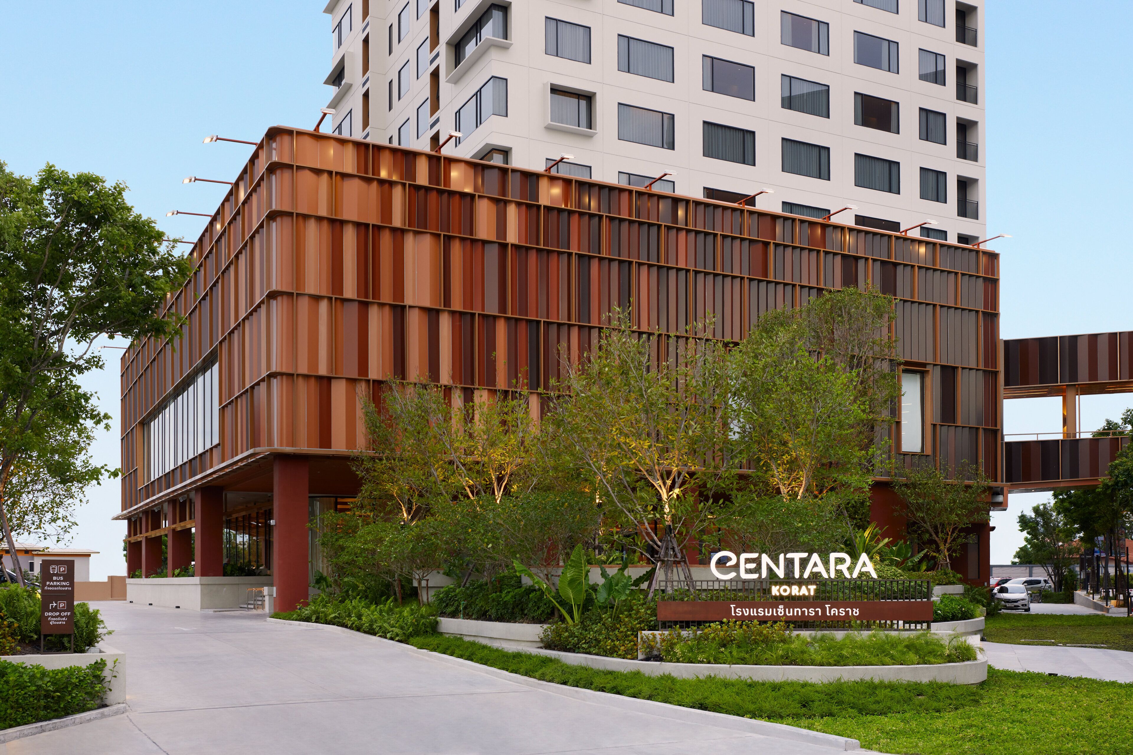 Un edificio moderno con un letrero que dice 'CENTARA' y un área ajardinada con árboles y un sendero.
