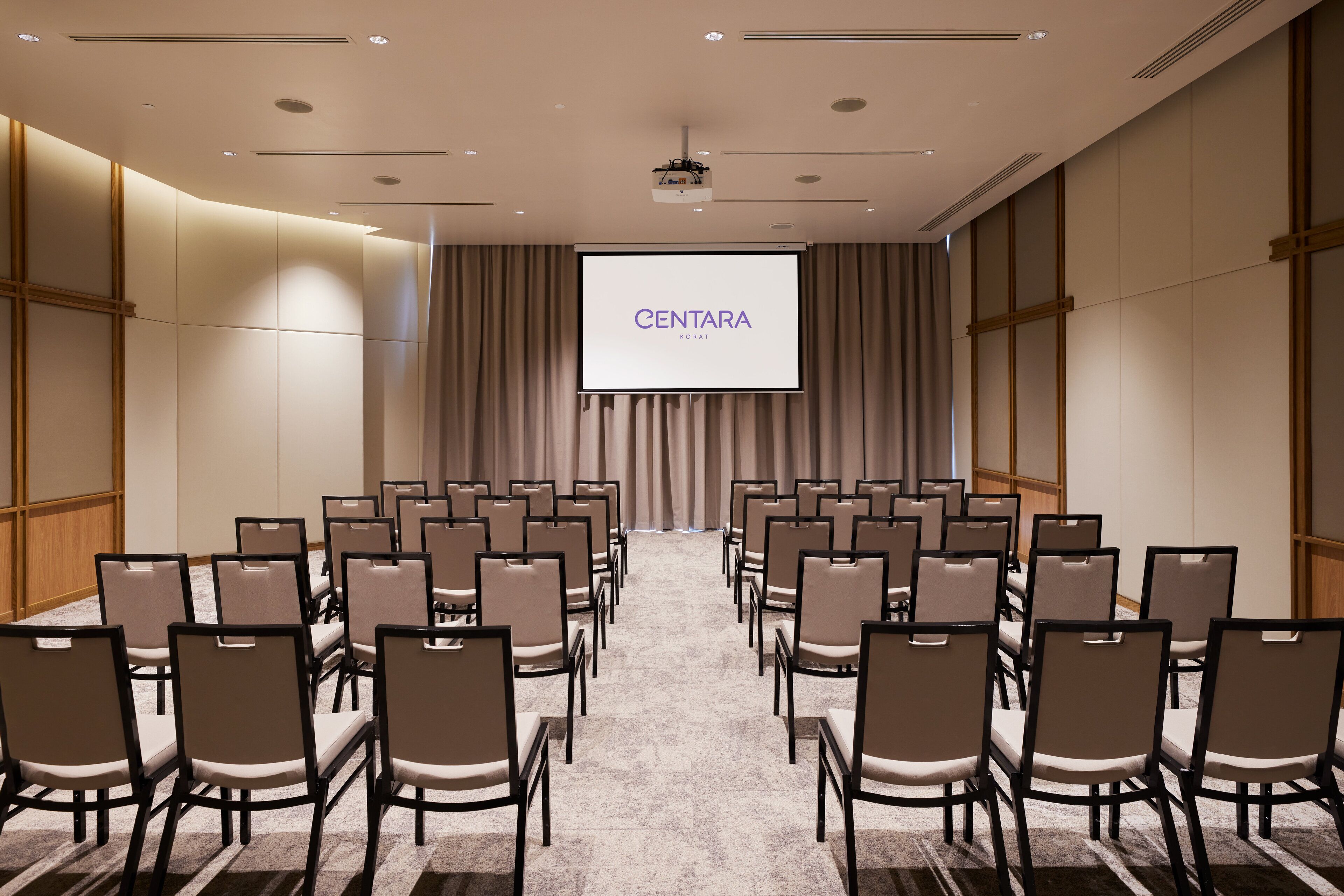 A conference room with rows of chairs facing a screen displaying "CENTARA".