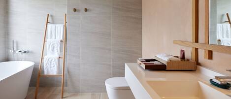 A modern bathroom with a freestanding bathtub, a wooden ladder with towels, a large mirror, and a white sink.