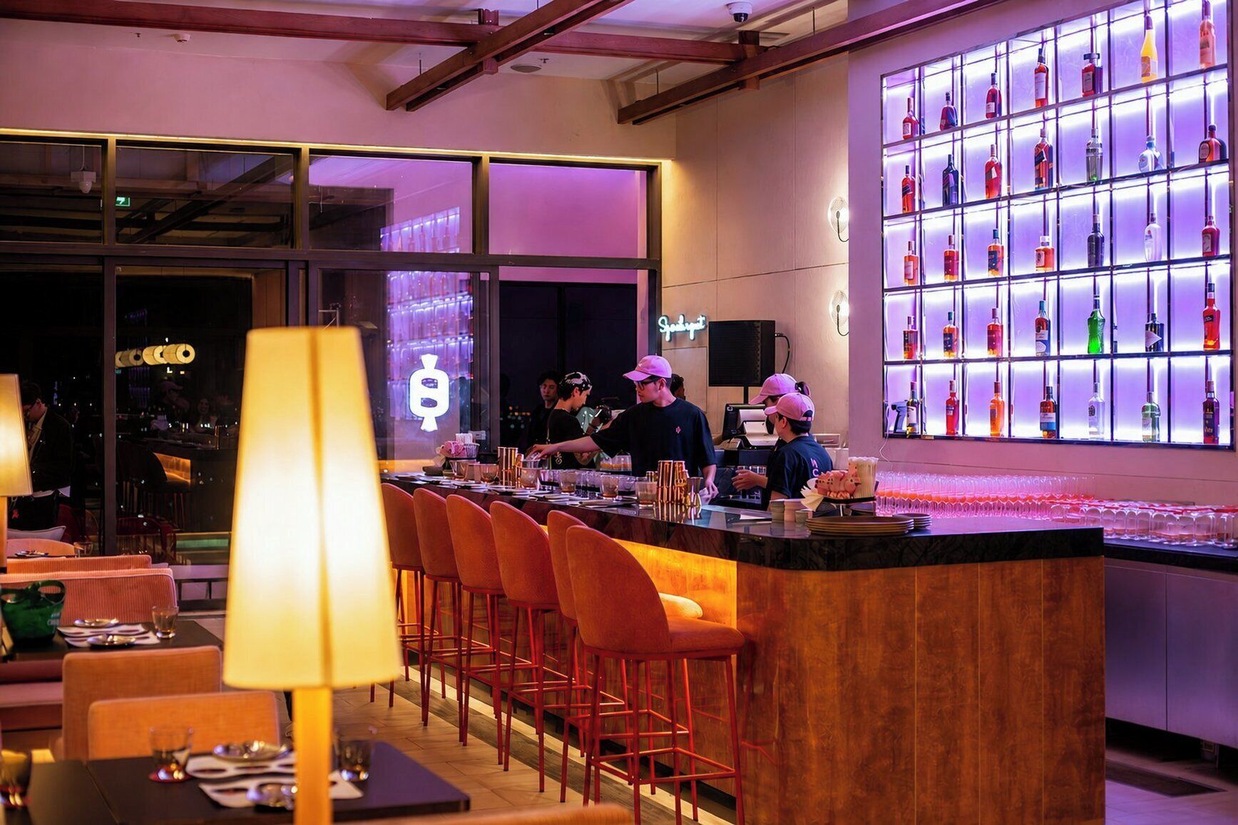 A bar area with a counter, stools, and a wall of liquor bottles.