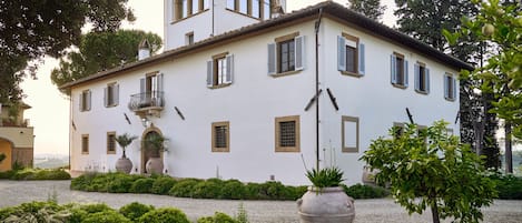Un bâtiment à deux étages doté d’une façade symétrique, de nombreuses fenêtres avec volets et d’une entrée centrale surmontée d’un petit porche.